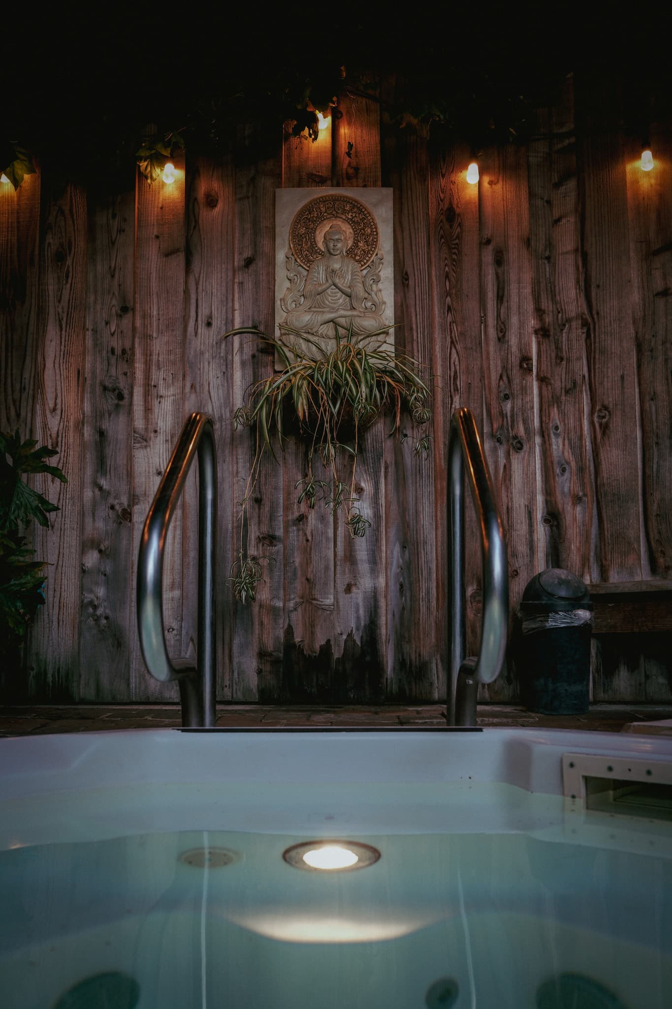 A private outdoor hot tub glowing beneath warm lights at dusk