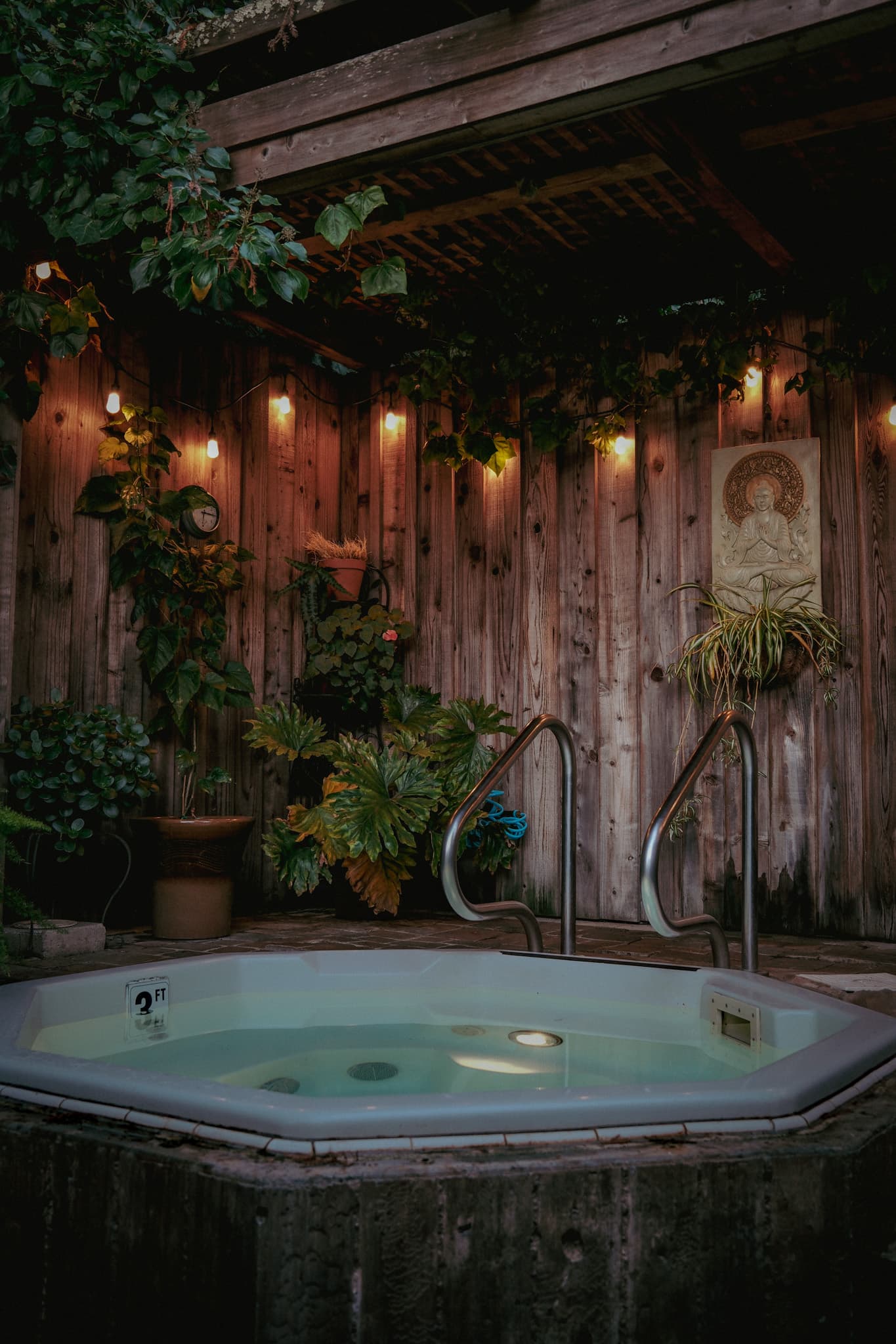 A private outdoor hot tub beneath ivy and warm evening lights
