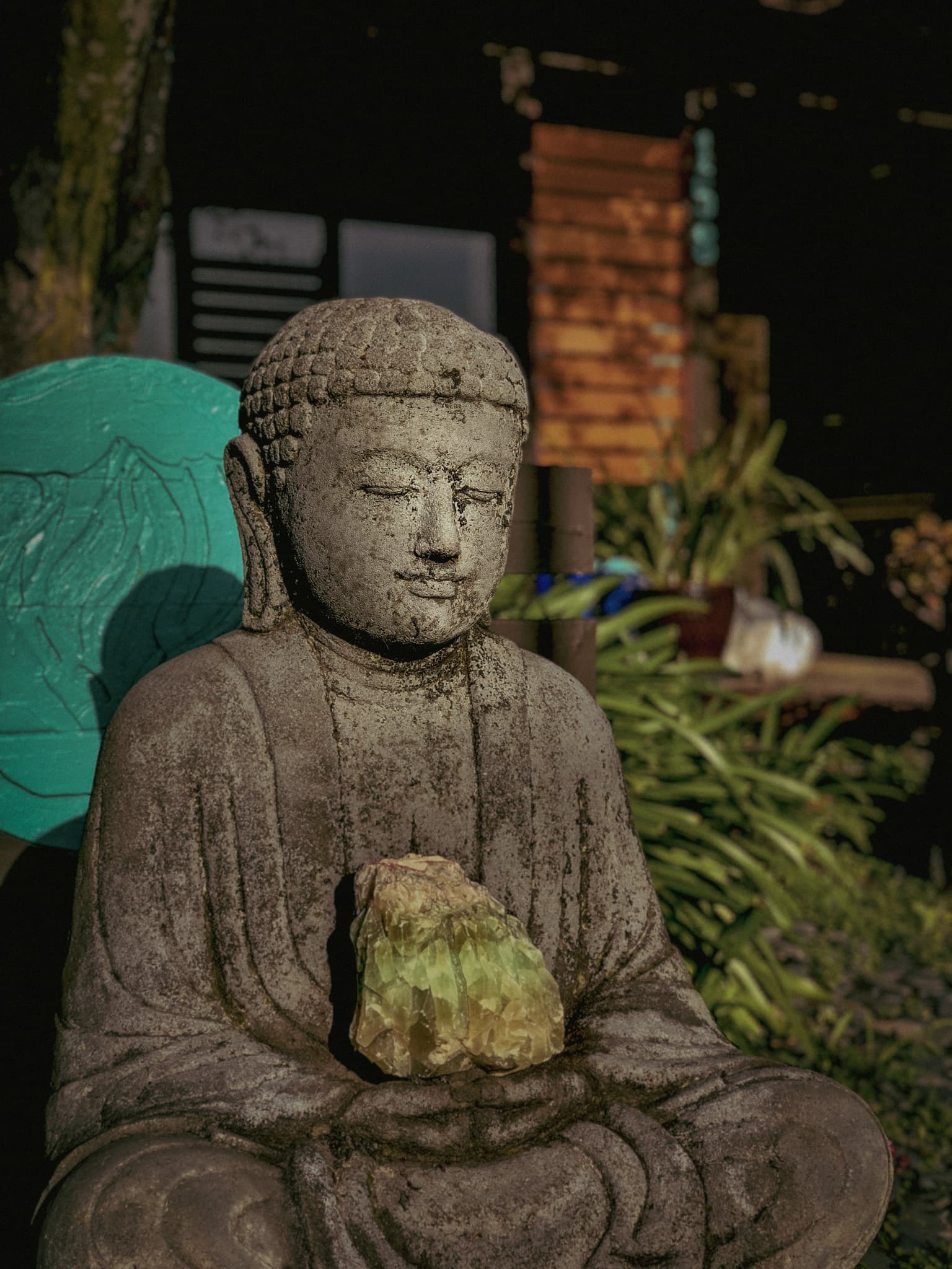 A weathered stone Buddha holding a crystal in the garden