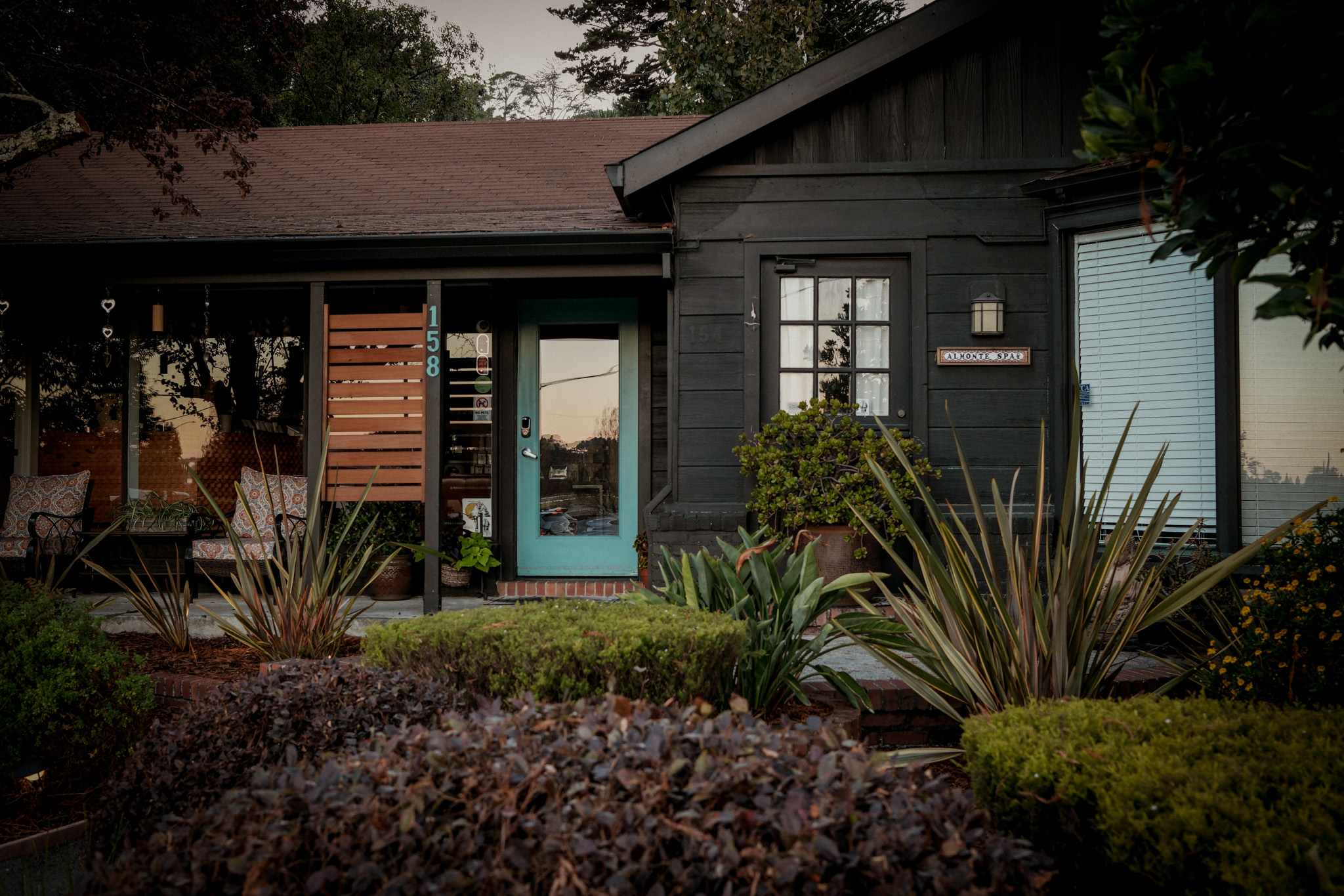 The modest dark-wood Almonte Spa house framed by its current garden