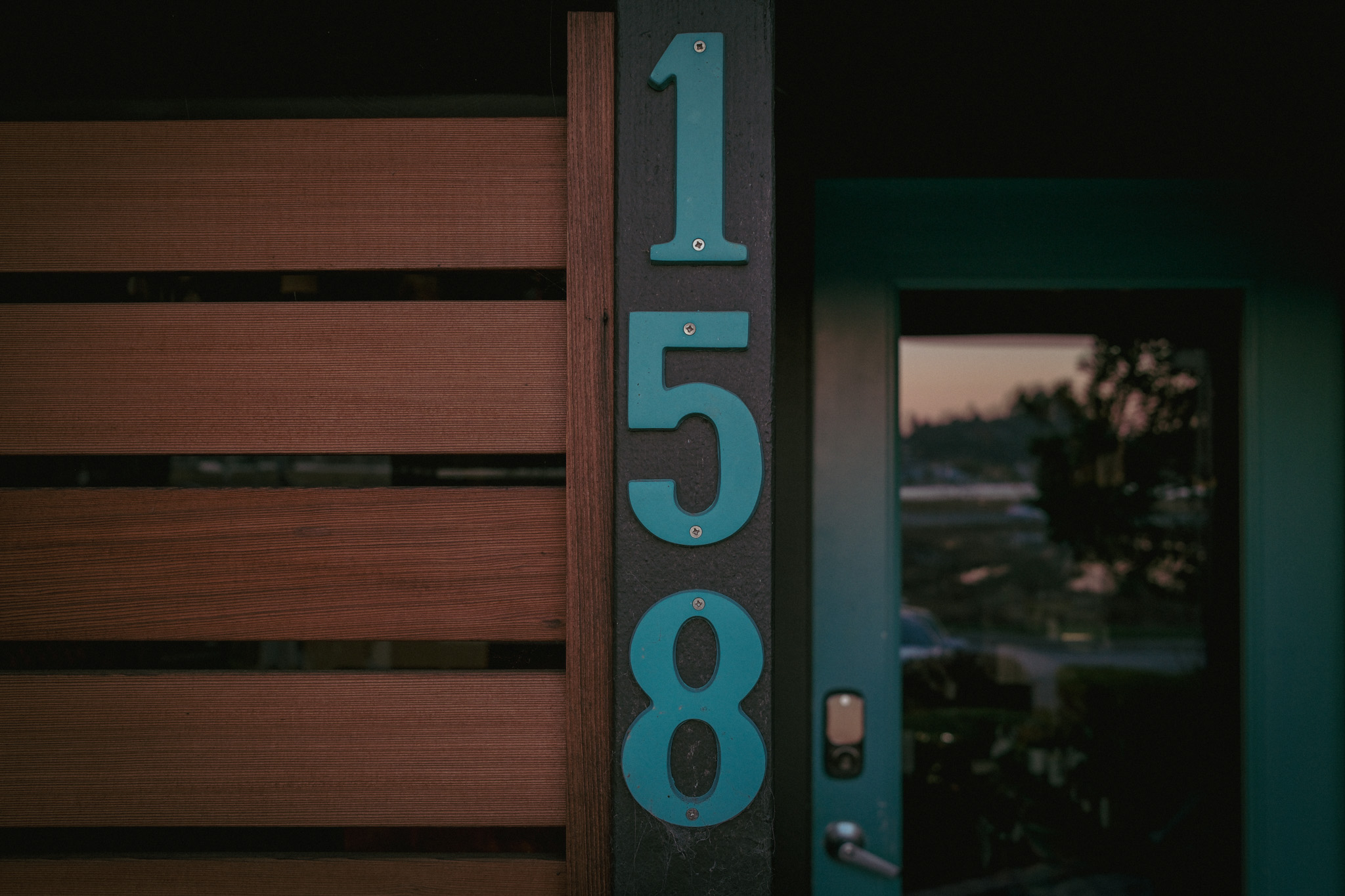 A close view of the handmade 158 address beside the blue door