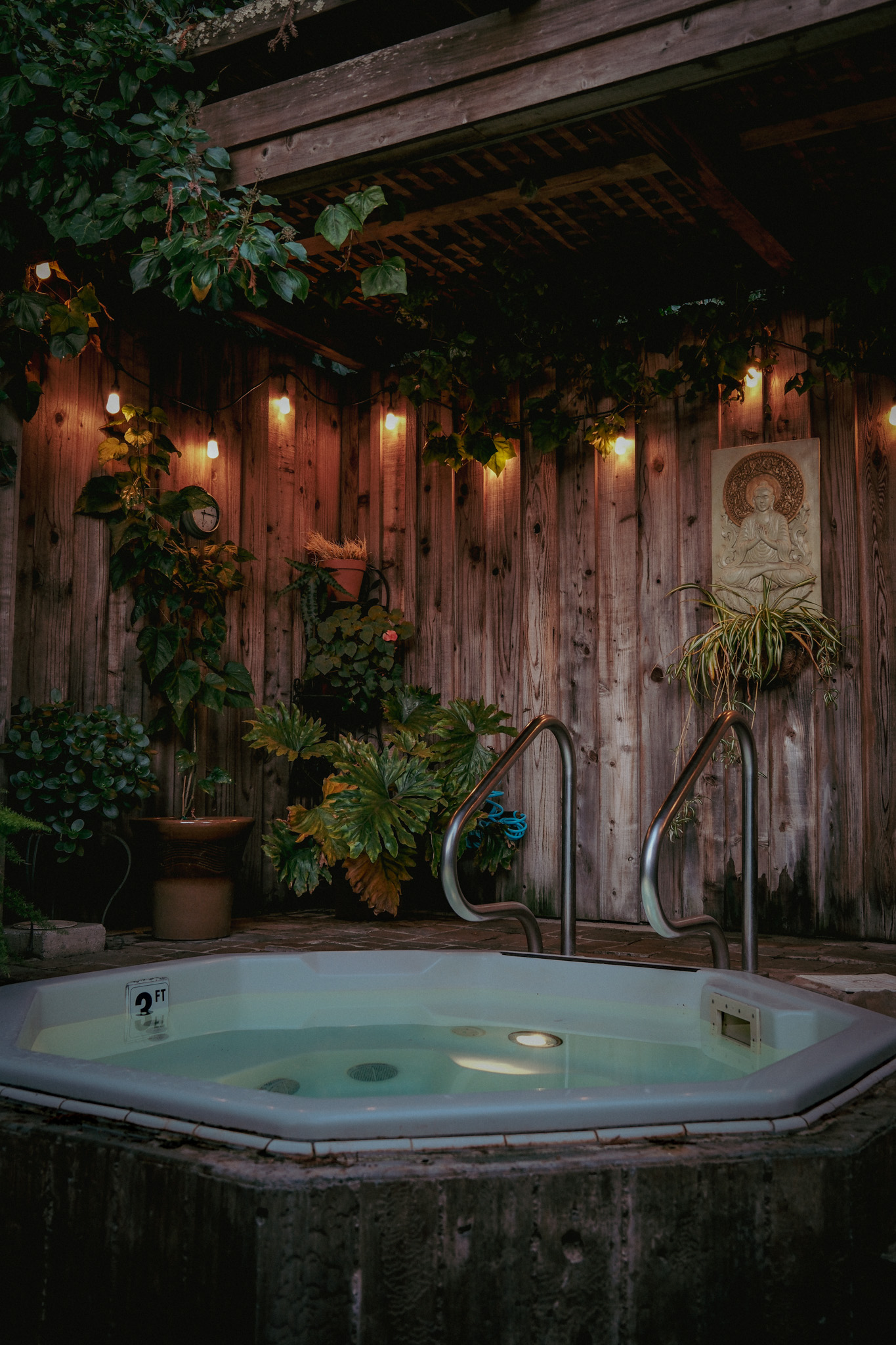 A private outdoor hot tub beneath ivy and warm evening lights