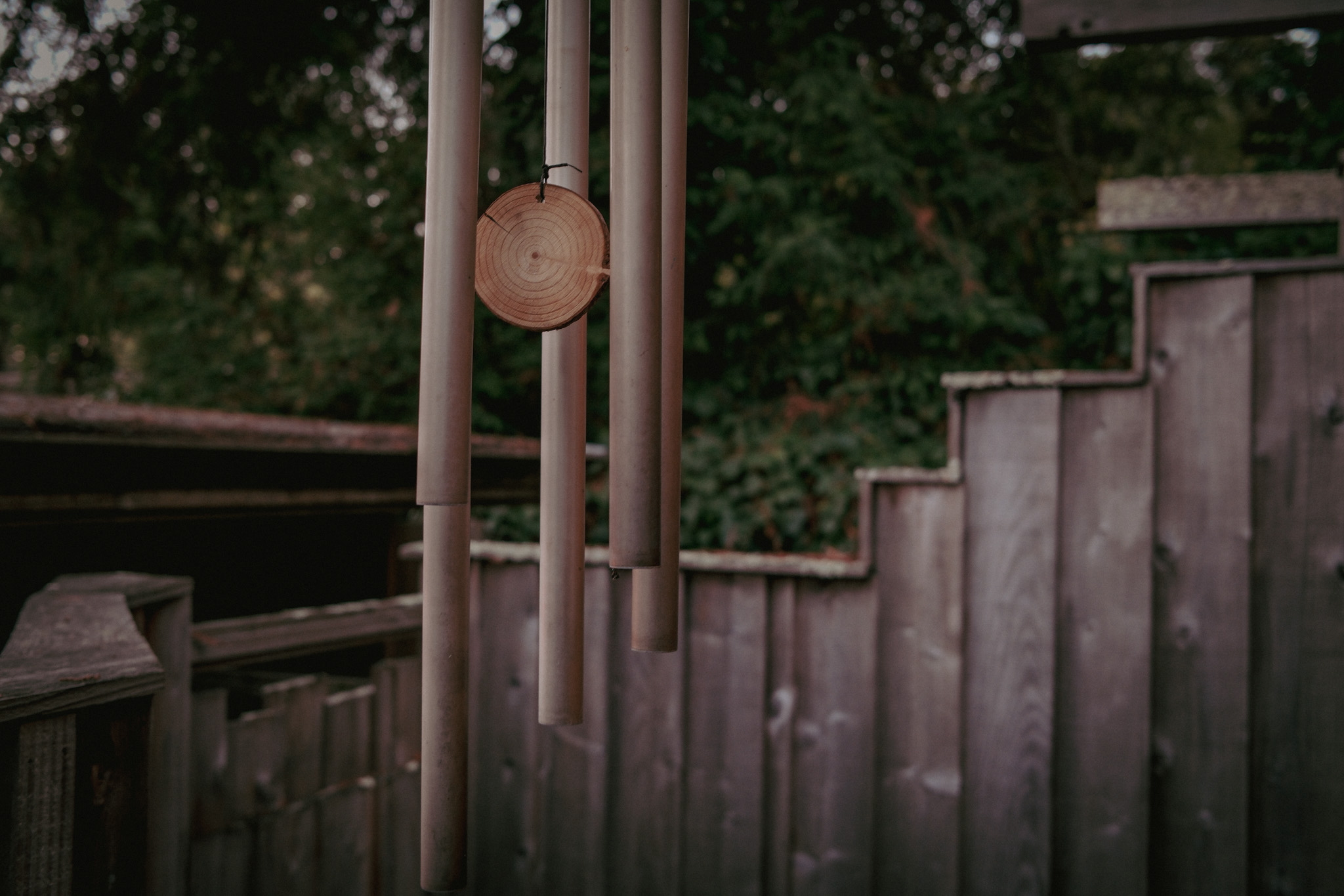 Small wind chimes hanging against weathered cedar