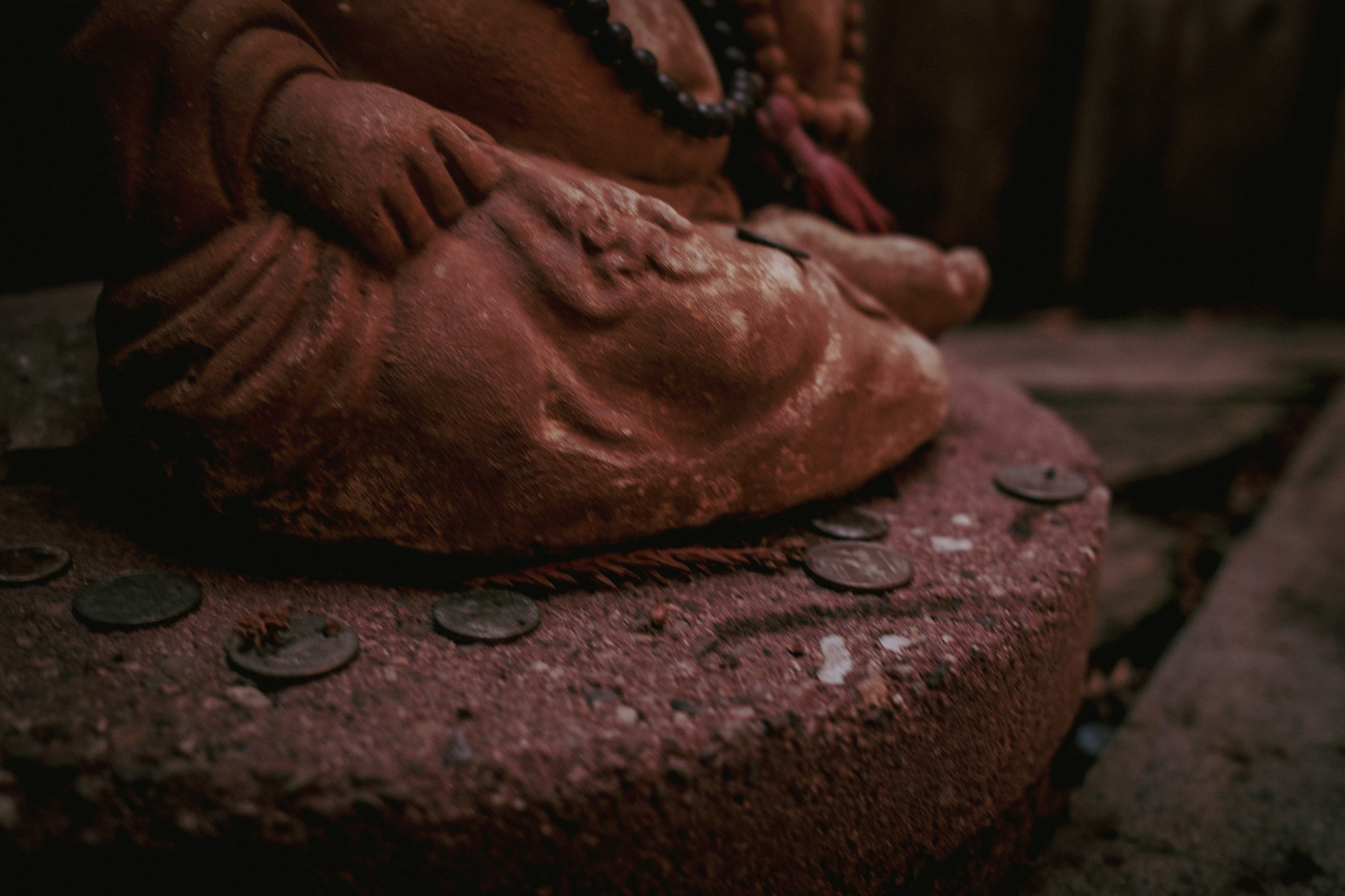 A small weathered Buddha surrounded by coins